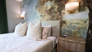 Ein Bett mit einer gebügelten weißen Bettdecke, einem Kopfteil und zwei Wandleuchten.