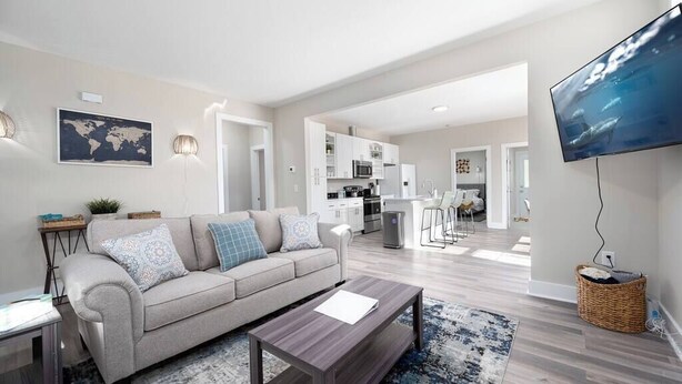 A modern living room with a sofa, coffee table, and a TV mounted on the wall.