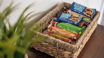 A woven basket containing snack packages on a wooden surface.