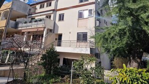 A multi-story residential building with balconies, a garden area, and a tree. - KATARINA B4 - Studio Apartment (Rovinj)
