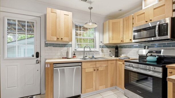 A modern kitchen with wooden cabinets, stainless steel appliances, and a built-in dishwasher.