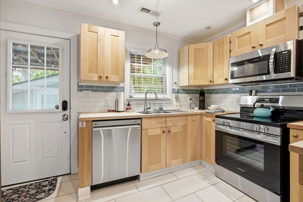 A modern kitchen with wooden cabinets, stainless steel appliances, and a built-in dishwasher.