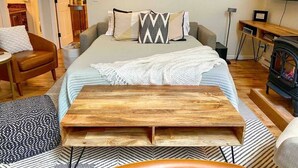 Ein Schlafzimmer mit einem Bett, einer Holzbank, einem Fernseher und einem Kamin.