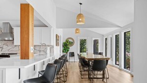 A modern kitchen with a marble countertop, black chairs, and a wooden column. - Ultimate Lakeview w/ Private Outdoor Pool, Hot Tub, Yard, Karaoke, Billiards, Arcade & Free Tickets (Branson)