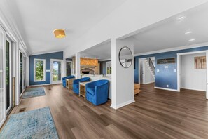 A spacious living area with a fireplace, blue sofas, and a staircase leading to another level. - Ultimate Lakeview w/ Private Outdoor Pool, Hot Tub, Yard, Karaoke, Billiards, Arcade & Free Tickets (Branson)