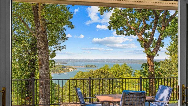 A deck with a table and chairs, overlooking a lake and trees. - Ultimate Lakeview w/ Private Outdoor Pool, Hot Tub, Yard, Karaoke, Billiards, Arcade & Free Tickets (Branson)