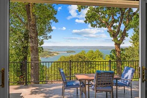 Une terrasse avec une table et des chaises, donnant sur un lac et une forêt.