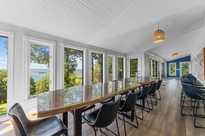 A long dining table with chairs, large windows, and a view of the outdoors.