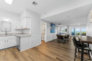 A modern kitchen with white cabinetry, a granite countertop, and a dining area with a wooden table and chairs. - Ultimate Lakeview w/ Private Outdoor Pool, Hot Tub, Yard, Karaoke, Billiards, Arcade & Free Tickets (Branson)