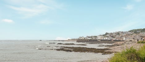 Une ville côtière avec un littoral rocheux, un ciel dégagé et des bâtiments en arrière-plan.