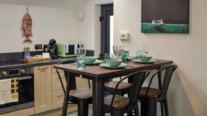 A modern kitchen with a skylight, a dining table set for four, and a painting on the wall.