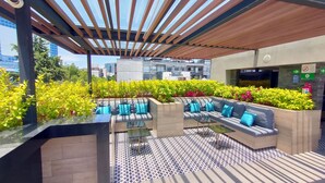 An outdoor seating area with a modern design, featuring a pergola, a patterned floor, and lush greenery. - Alia Inn Boutique WTC (Mexico City)