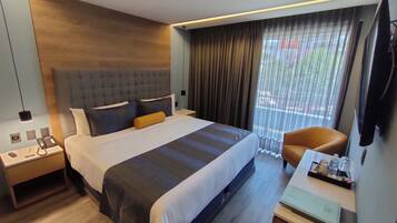 Een moderne hotelkamer met een groot bed, een bureau met telefoon en een stoel.