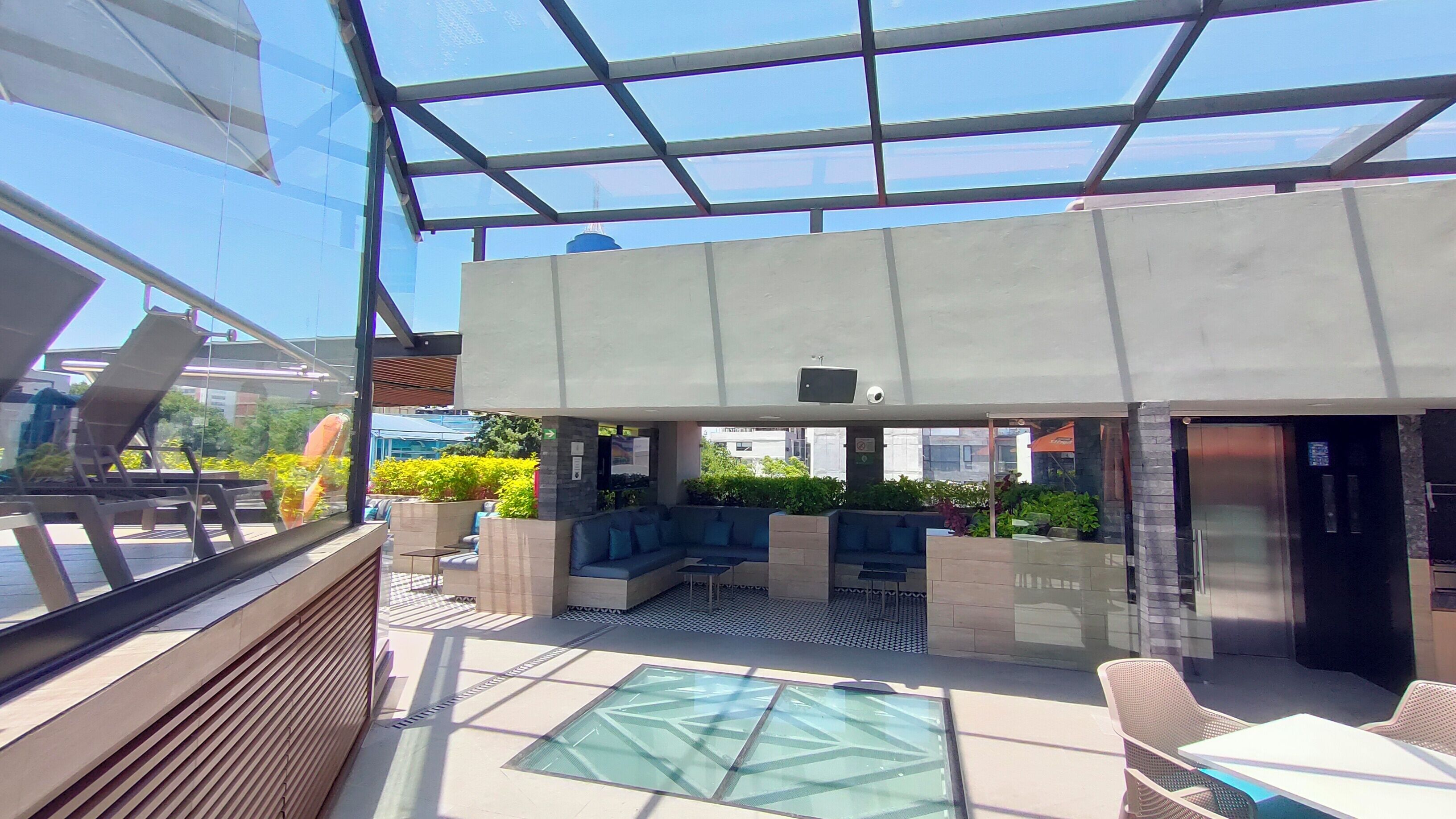 Un espacio lounge moderno al aire libre con asientos y techo de cristal.