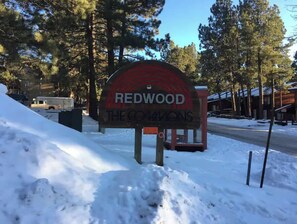 Welcome to Redwood The Commons, a charming destination surrounded by trees and a red-roofed building.