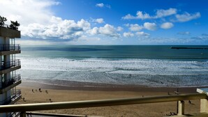 A beach view with a clear sky, a sandy shore, and a building with balconies overlooking the sea. - Renovated studio facing the main beach in Les Sables d'Olonne (Les Sables-d´Olonne)