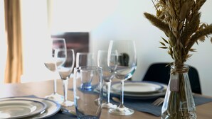 A dining table set with plates, cutlery, and wine glasses, with a vase of dried flowers in the center. - Renovated studio facing the main beach in Les Sables d'Olonne (Les Sables-d´Olonne)