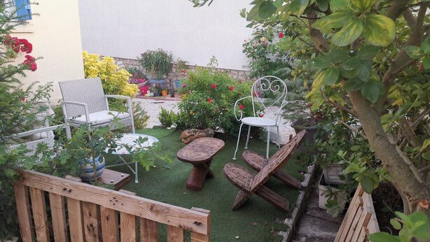 A garden patio with wicker chairs, a small round table, and a wooden fence.