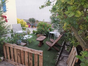 Un patio jardín con sillas de mimbre, una pequeña mesa redonda y una valla de madera.