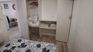 A bedroom with a bed, a wardrobe, a desk, and a chair.