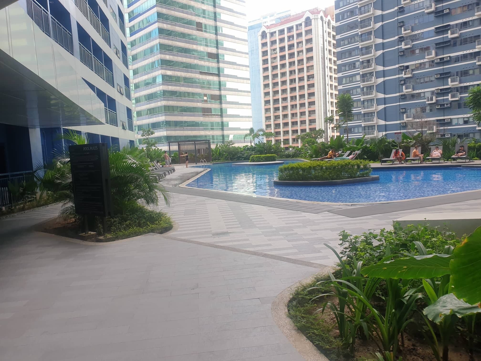 Um edifício moderno com piscina rodeada por vegetação.