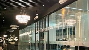 Un intérieur moderne avec des murs en verre réfléchissant, un escalier central et des luminaires contemporains.