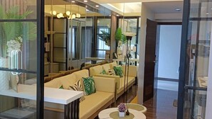 Une chambre d’hôtel moderne avec une cloison en verre, un canapé, une petite table ronde et un lit.
