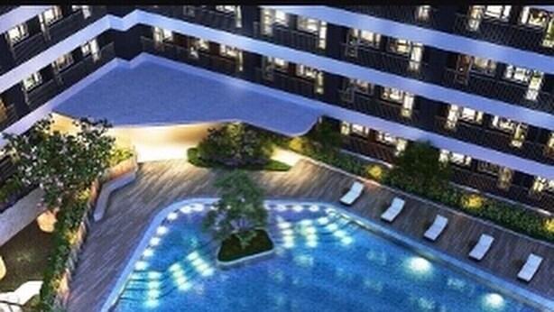 Un hôtel moderne doté d’une grande piscine intérieure, de nombreux balcons et d’une végétation luxuriante.
