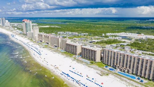 A coastal resort with beachfront hotels, a sandy beach, and a large pool area.