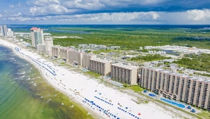 A coastal resort with beachfront hotels, a sandy beach, and a large pool area. - Beach House Retreat, Walk to Beach, Pool, Balcony, Pet Friendly (Orange Beach)
