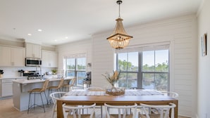 A spacious kitchen with white cabinetry, a wooden island, and a large window offering a view of the outdoors.