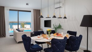 Un comedor con una mesa preparada para cuatro personas, un sofá y vista al mar.