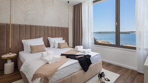 Ein modernes Schlafzimmer mit einem großen Bett, einem Nachttisch und Blick aufs Meer.