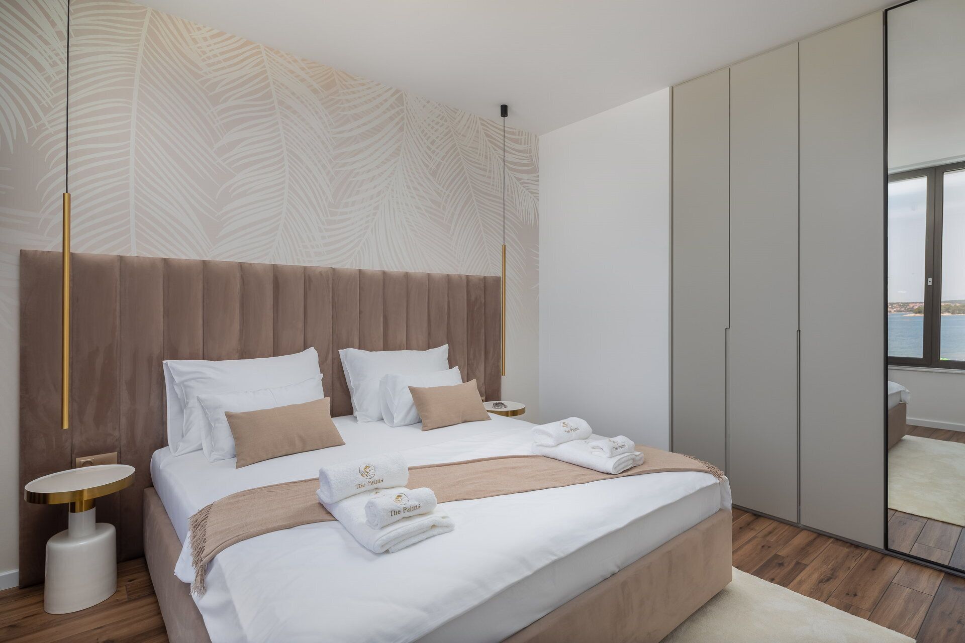 Ein modernes Schlafzimmer mit einem großen Bett, einem Kopfteil, einem Nachttisch und einem Spiegel.