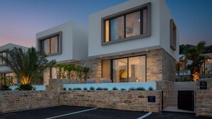 Una casa moderna de dos pisos con fachada de piedra, ventanas grandes y un interior bien iluminado.