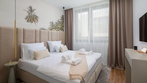 Ein Hotelzimmer mit einem großen Bett, einem Schreibtisch und einem Fenster mit transparenten Vorhängen.