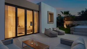 Un área exterior moderna con un sofá, una mesa de centro y una mesa de comedor.