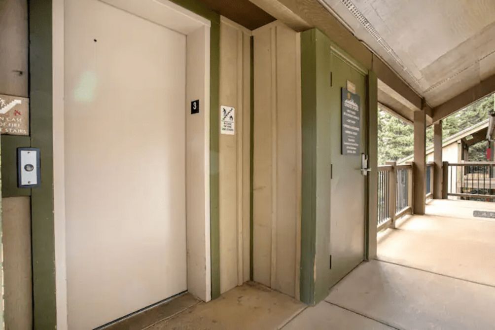 A hallway with a door marked with the number 3, a sign indicating a no-smoking area, and a security intercom.