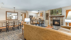 A living room with a fireplace, a dining area, and a kitchen.