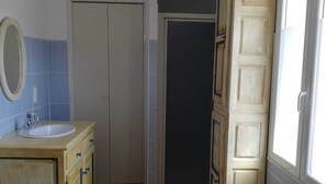 A bathroom with a wooden vanity, a sink, a mirror, and a blue mat on the floor. - Town house in the heart of a typical Lot village (Saint-Sozy)