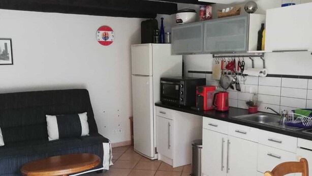 A compact living space with a kitchenette, a sofa, a dining table, and a chair. - Town house in the heart of a typical Lot village (Saint-Sozy)