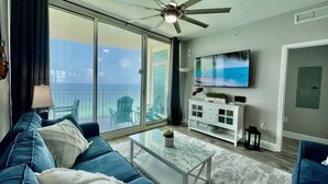 Ein modernes Wohnzimmer mit einem großen Schiebeglastür, die auf einen Balkon mit Meerblick führt.