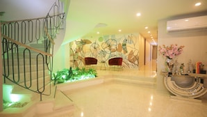 Eine moderne Lobby mit einer Treppe, zwei roten Stühlen, einer floralen Wandmalerei und einer dekorativen Vase.