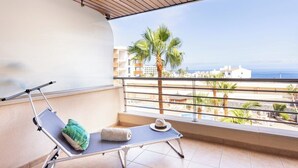 Ein Balkon mit Liegestuhl, Handtuch und Hut.