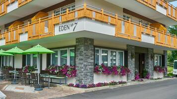 Un hôtel doté d’une terrasse, de piliers en pierre et de balcons en bois.