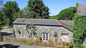 A stone building with a sloped roof, a small door, and a window.