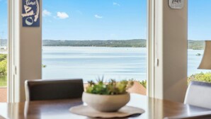 Uma área de jantar com vista para um lago, uma tigela com plantas na mesa e uma placa na parede.