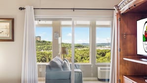 Quarto com janela ampla, cama, sofá e televisão.