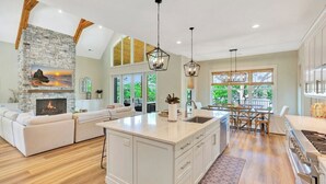 A spacious kitchen with a large island, a stone fireplace, and a dining area with natural light.