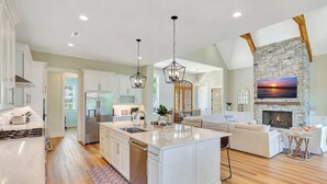 A spacious kitchen with a large island, a stone fireplace, and a cozy seating area.